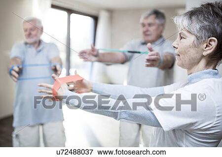 Stock Photo - Senior adults using resistance bands in exercise class.. Fotosearch