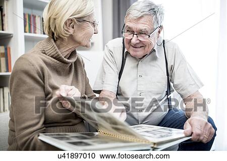 Stock Image - Senior couple looking at photo album.. Fotosearch
