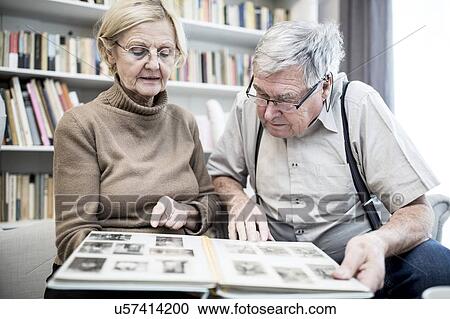 Stock Image - Senior couple looking at photo album.. Fotosearch