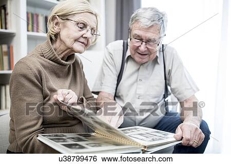Stock Photograph - Senior couple looking at photo album.. Fotosearch
