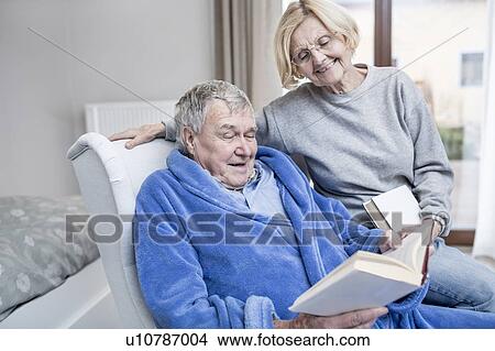 Picture - Senior couple reading book in care home.. Fotosearch