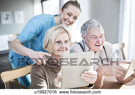 Senior couple using digital tablets in care home. View Large Photo Image Stock Photograph - Senior couple using digital tablets in care home.. Fotosearch