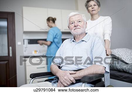Picture - Senior man in wheelchair with woman in care home.. Fotosearch