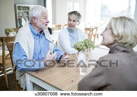 Stock Photo - Senior man talking to two female friends in care home.. Fotosearch
