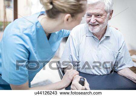 Stock Image - Senior man using rollator with care worker assisting.. Fotosearch