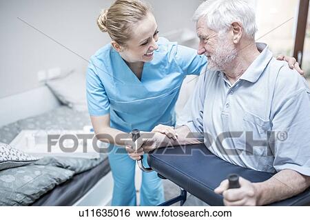 Stock Photograph - Senior man using rollator with care worker assisting.. Fotosearch