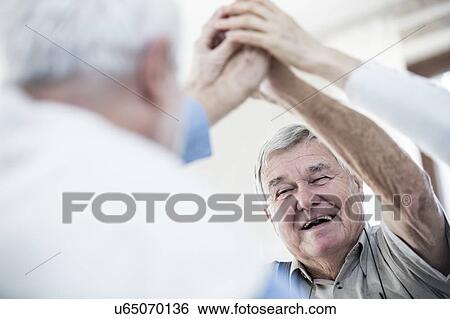 Stock Photograph - Senior men giving high five.. Fotosearch