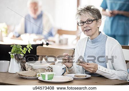 Stock Photo - Senior woman eating meal in care home.. Fotosearch