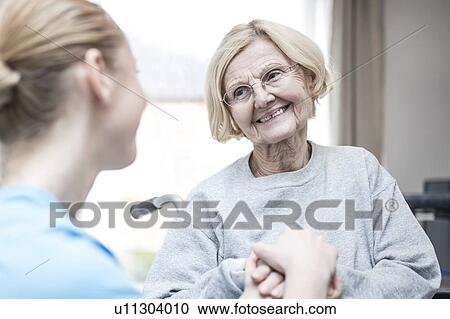 Stock Image - Senior woman smiling at care worker.. Fotosearch