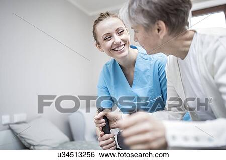 Stock Photograph - Senior woman using rollator with care worker assisting.. Fotosearch