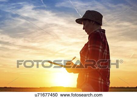 Stock Image - Silhouetted farmer writing notes.. Fotosearch