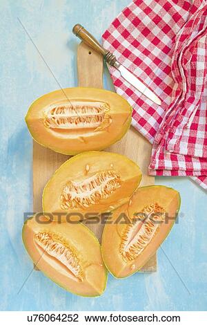 Stock Image - Slices of cantaloupe melon on rustic table.. Fotosearch