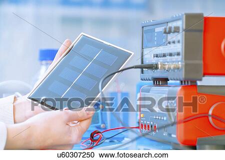 Stock Image - Solar battery research. Researcher holding a silicon photovoltaic element.. Fotosearch