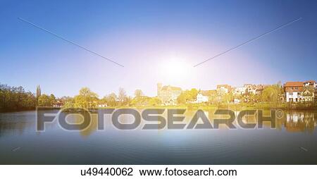 Stock Image - Sunrise over lake in town.. Fotosearch