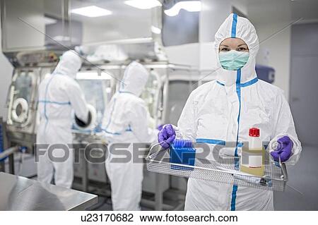 Stock Image - Technician carrying equipment in a laboratory that manufactures human tissues for implant. In the bottle is physiological solution, which helps to maintain cells in vitro. Tissues manufactured at the facility include bone and skin grafts.. Fotosearch