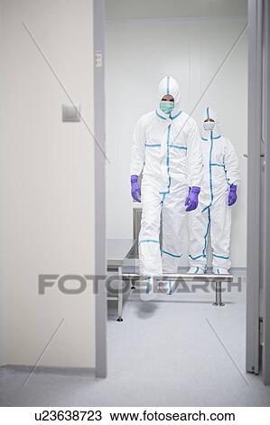 Stock Image - Technicians walking through a decontamination cabin before entering a sterile laboratory.. Fotosearch