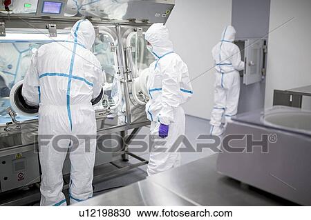 Stock Image - Technicians working in sealed, sterile isolator units in a laboratory that manufactures human tissues for implant. Such tissues include bone and skin grafts.. Fotosearch