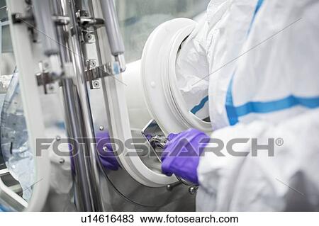 Stock Image - Technicians working in sealed, sterile isolator units in a laboratory that manufactures human tissues for implant. Such tissues include bone and skin grafts.. Fotosearch