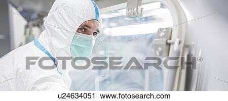 Stock Image - Technicians working in sealed, sterile isolator units in a laboratory that manufactures human tissues for implant. Such tissues include bone and skin grafts.. Fotosearch
