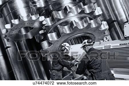 Stock Image - Two workers operating giant steel mill machinery.. Fotosearch