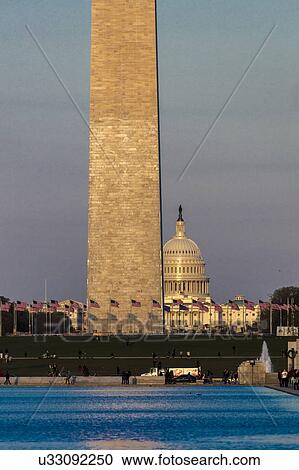 Stock Image - US Flags with cropped view of US Capitol and Washington Monument surrounded by visitors to Washington, D. C. . Fotosearch