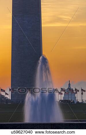 Stock Image - US Flags with cropped view of US Capitol and Washington Monument surrounded by visitors to Washington, D. C. . Fotosearch