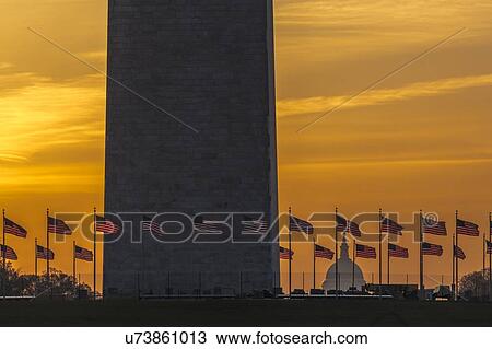 Stock Image - US Flags with cropped view of US Capitol and Washington Monument surrounded by visitors to Washington, D. C. . Fotosearch