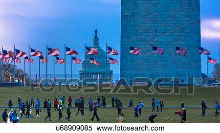 Stock Photography - US Flags with cropped view of US Capitol and Washington Monument surrounded by visitors to Washington, D. C. . Fotosearch