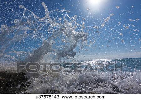 Stock Image - Waves breaking against rocks.. Fotosearch