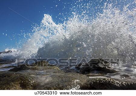 Stock Image - Waves breaking against rocks.. Fotosearch