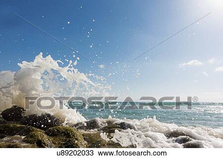Stock Image - Waves breaking against rocks.. Fotosearch