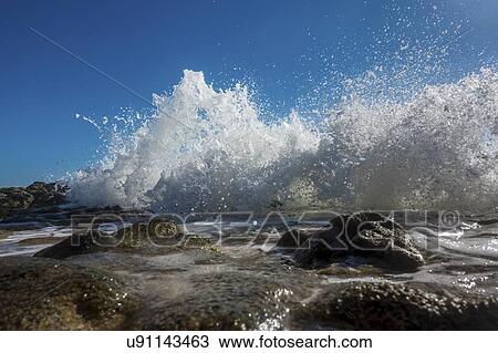 Stock Image - Waves breaking against rocks.. Fotosearch