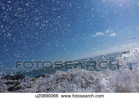 Stock Photograph - Waves breaking against rocks.. Fotosearch