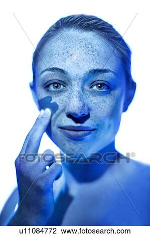 Stock Image - Woman applying sunscreen to her cheek.. Fotosearch