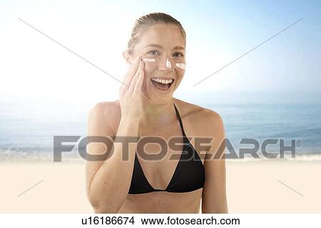 Picture - Woman applying sunscreen to her face.. Fotosearch