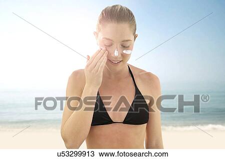 Stock Image - Woman applying sunscreen to her face.. Fotosearch