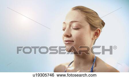 Stock Photograph - Woman in sunlight with eyes closed.. Fotosearch
