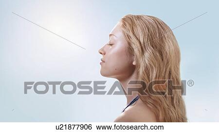 Stock Photograph - Woman in sunlight with eyes closed.. Fotosearch