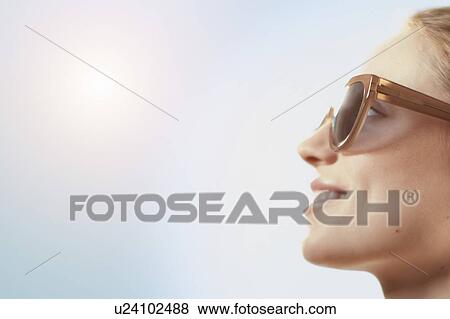Stock Photo - Woman wearing sunglasses, smiling.. Fotosearch