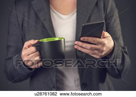 Stock Image - Woman with mug and smartphone.. Fotosearch