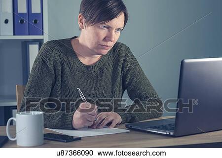 Stock Image - Woman working at desk.. Fotosearch