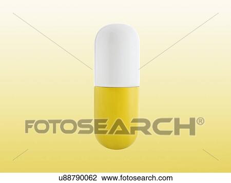 Stock Image - Yellow and white capsule, studio shot.. Fotosearch