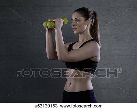 Young woman in sports top holding hand weights, portrait. View Large Photo Image Stock Image - Young woman in sports top holding hand weights, portrait.. Fotosearch