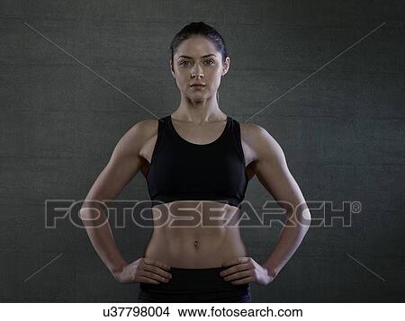 Picture - Young woman in sports top with hands on hips, portrait.. Fotosearch