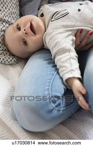 Baby girl (12-17 months) lying down on mum's lap View Large Photo Image Picture - Baby girl (12-17 months) lying down on mum's lap. Fotosearch