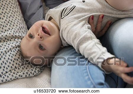 Baby girl (12-17 months) lying down on mum's lap View Large Photo Image Stock Image - Baby girl (12-17 months) lying down on mum's lap. Fotosearch