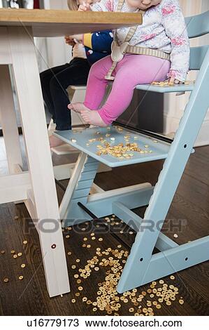Stock Image - Baby girl (12-17 months) watching spilled cereal. Fotosearch
