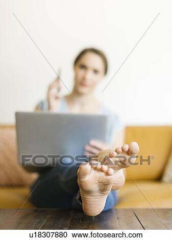 Stock Image - Barefoot woman using laptop. Fotosearch