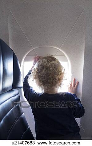 Stock Image - Boy by window on airplane. Fotosearch