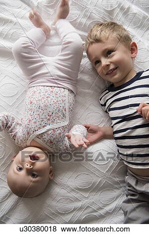 Boy lying beside little sister (18-23 months, 4-5) View Large Photo Image Stock Photo - Boy lying beside little sister (18-23 months, 4-5). Fotosearch